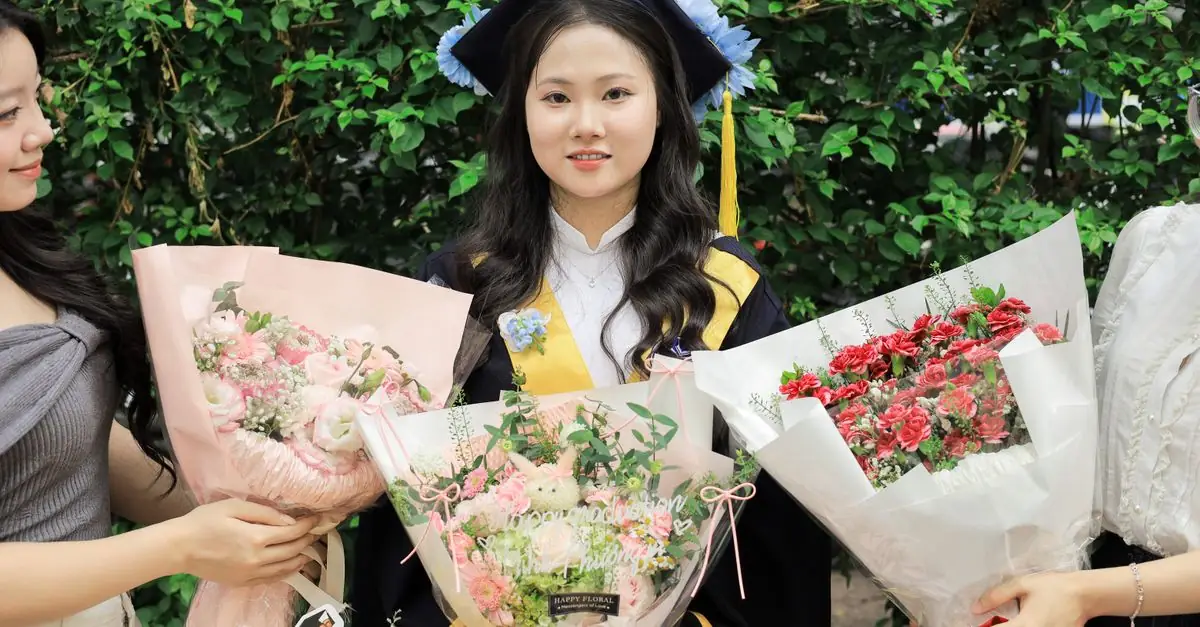 卒業式を終えた学生へ春色の花束を手渡す場面